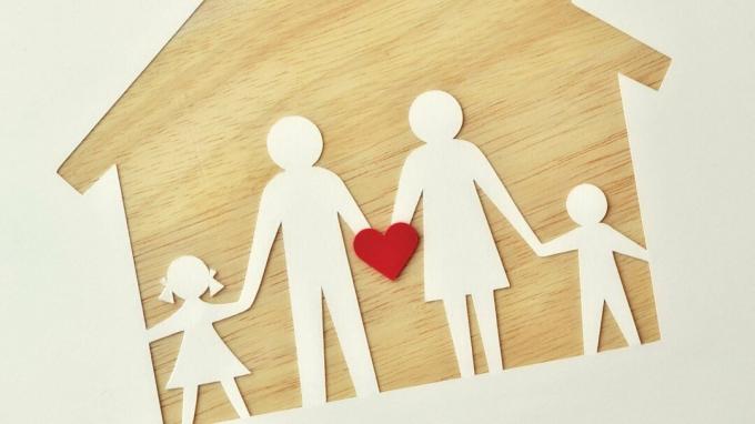 Una familia de papel en una casa de madera, sosteniendo un corazón para representar el amor, el apoyo y la ayuda para el TDAH