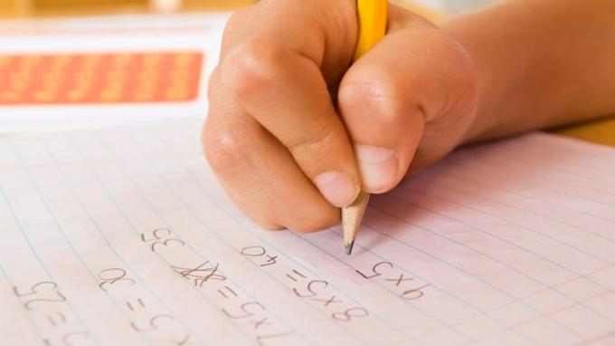 La mano de un niño completando una tarea con la ayuda de adaptaciones matemáticas