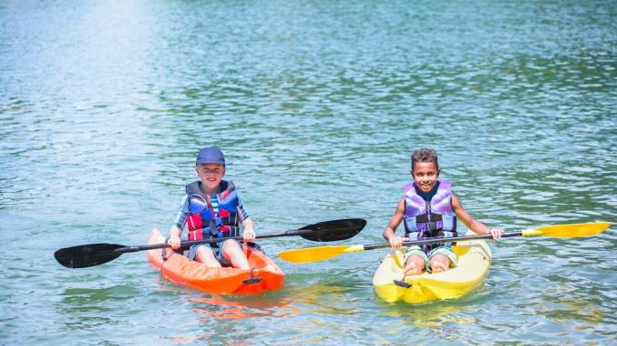 Dos niños en kayak en un lago como parte de una actividad de campamento de verano