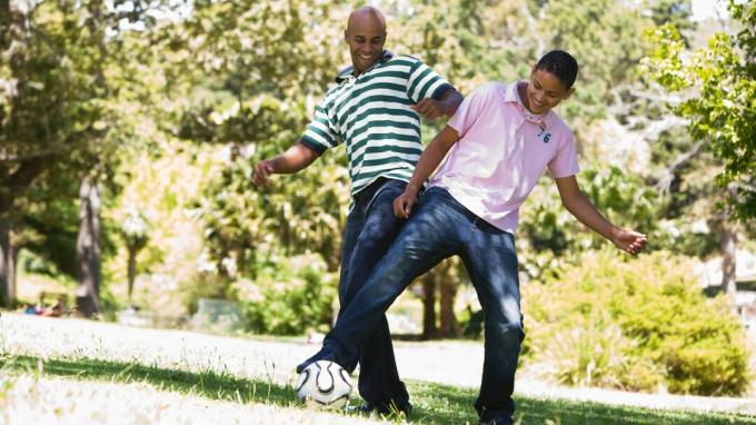 Un padre criando a su adolescente jugando un divertido juego de fútbol